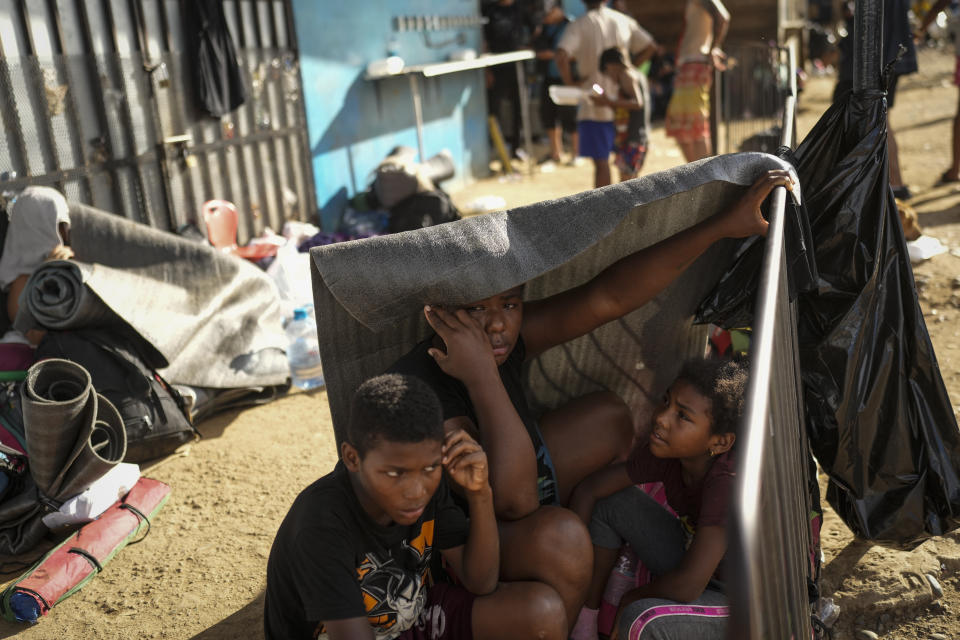 Venezuelan migrant Nathaly Rojas shields herself from the sun with her children in a temporary camp after crossing the Darien Gap from Colombia in Lajas Blancas, Panama, Thursday, June 27, 2024. (AP Photo/Matias Delacroix)