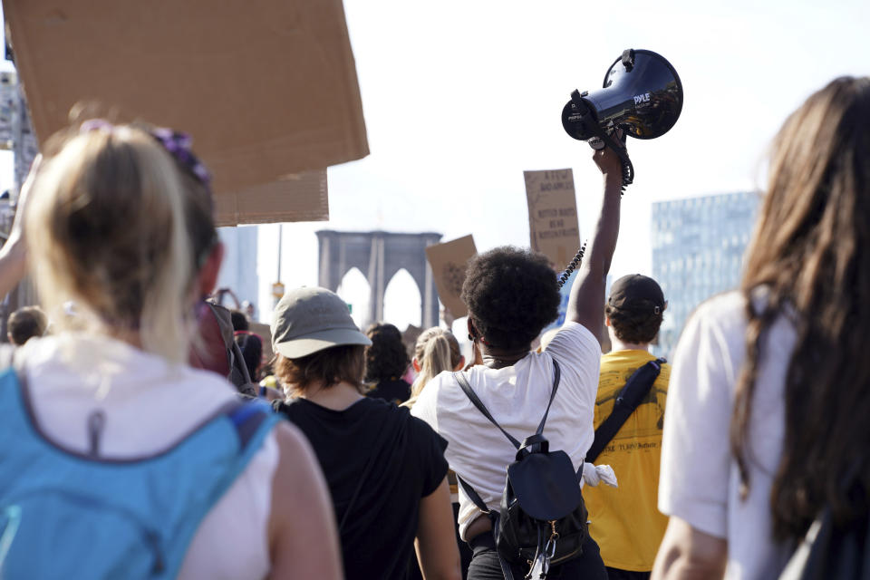 Activist and minister Kianna Ruff raises a megaphone as she and hundreds of others cross the Brooklyn Bridge to protest police brutality and systemic racism on July 26, 2020, in New York. Many involved in the demonstrations that erupted after George Floyd's killing say they deepen spiritual connections and embody familiar elements of traditional faith. (AP Photo/Emily Leshner)