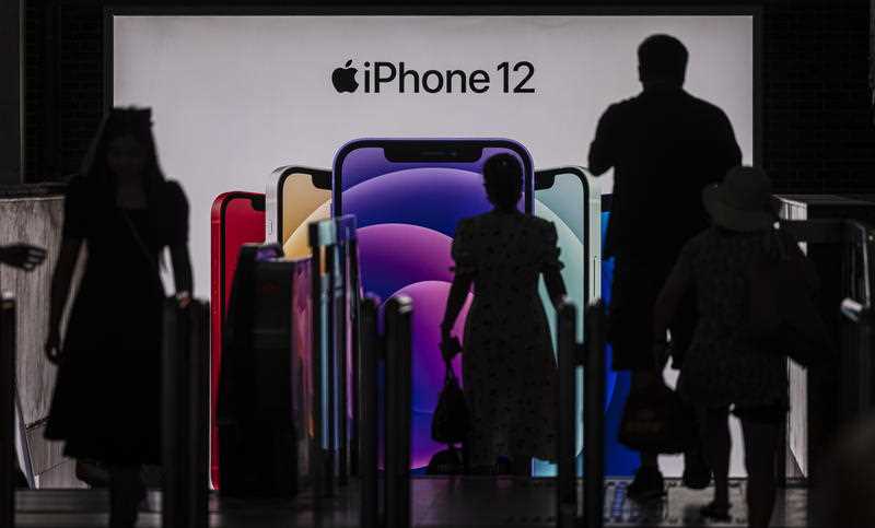 People enter the subway in front of a Apple's iPhone 12 advertisement, in Shanghai, China.