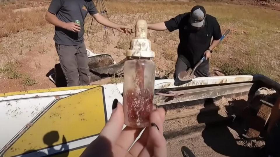 A bottle is held up after it is recovered from a boat that sank in Lake Powell 29 years earlier. The boat was retrieved in 2022 after Lake Powell water levels had receded.