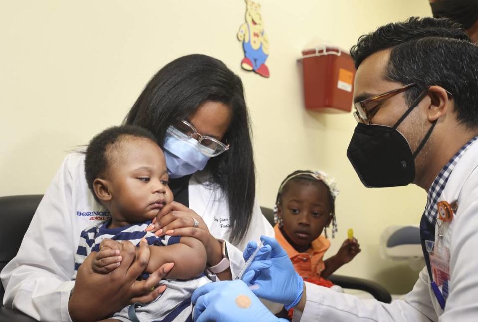 El Dr. Nizar Dowla, a la derecha, le administra la vacuna COVID-19 a Deji Adebayo, de nueve meses, mientras su madre, la Dra. Emy Jean-Marie, y su hermana, Emiola Adebayo, observan durante una campaña para niños menores de cinco años en martes 28 de junio de 2022 en Borinquen Health Care Center en Miami. La subsecretaria de Salud, la almirante Rachel Levine, y la alcaldesa de Miami-Dade, Daniella Levine Cava, asistieron a la campaña. Alie Skowronski/askowronski@miamiherald.com