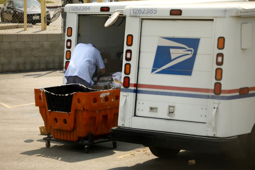 San Pedro, California,-Aug. 20, 2020-A Los Angeles Postal carrier organizes mail to be delivered on Aug. 20, 2020. United States Postal Workers were offered 12 weeks leave due to the coronavirus pandemic, which caused a backlog of mail that needed to be delivered. Many postal carriers were offered overtime. A lack of enough postal carriers is one of the reasons that the United States Postal Service is behind on delivering mail. (Carolyn Cole/Los Angeles Times)