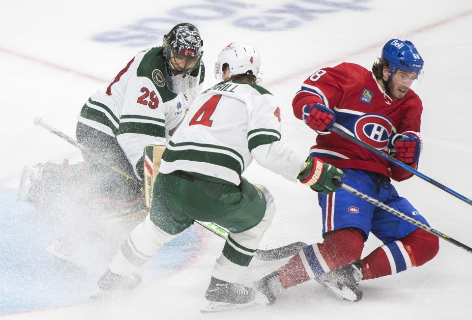 Montreal Canadiens' Mike Hoffman (68) is brought down by Minnesota Wild's Jon Merrill as he takes a shot on Wild goaltender Marc-Andre Fleury during the third period of an NHL hockey game, Tuesday, Oct. 25, 2022 in Montreal. (Graham Hughes/The Canadian Press via AP)