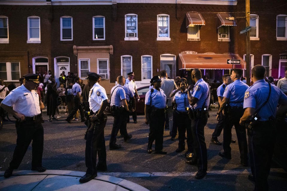 Officers gather for crowd control near a massive police presence set up outside a house as they investigate an active shooting situation, in Philadelphia, Wednesday, Aug. 14, 2019. (AP Photo/Matt Rourke)