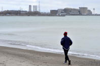 A jogger runs along the beach past the Pickering Nuclear Generating Station, in Pickering, Ontario, Sunday, Jan. 12, 2020. Ontario Power Generation said an alert warning Ontario residents of an unspecified "incident" at the nuclear plant early Sunday morning was sent in error. (Frank Gunn/The Canadian Press via AP)