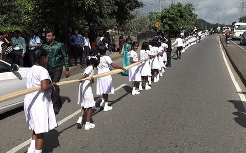 Sri Lankan children carry a wedding saree as a bride attempts to set a record for the longest wedding saree - Credit: STR/AFP/Getty Images