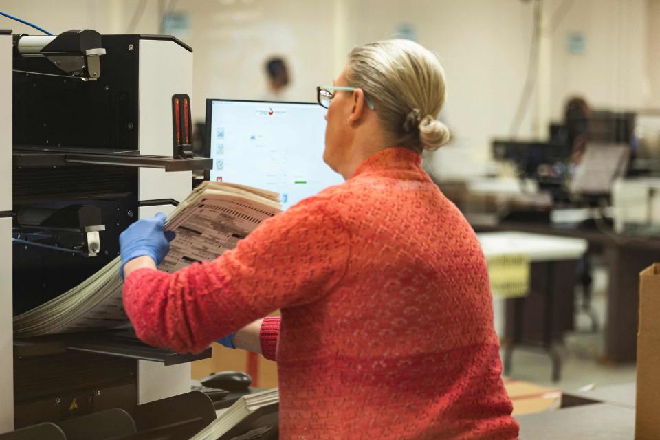 A poll worker handles ballots for the midterm election, in the presence of observers from both Democrat and Republican parties, at the Maricopa County Tabulation and Elections Center (MCTEC) in Phoenix, Arizona, on October 25, 2022.