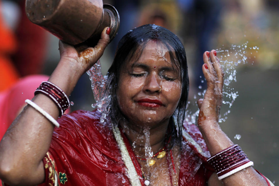 In this Nov. 13, 2018, file photo, a Nepalese woman takes a holy bath on the banks of the Bagmati River during Chhath Puja festival in Kathmandu, Nepal. During Chhath, an ancient Hindu festival, rituals are performed to thank the Sun God for sustaining life on earth. (AP Photo/Niranjan Shrestha, File)