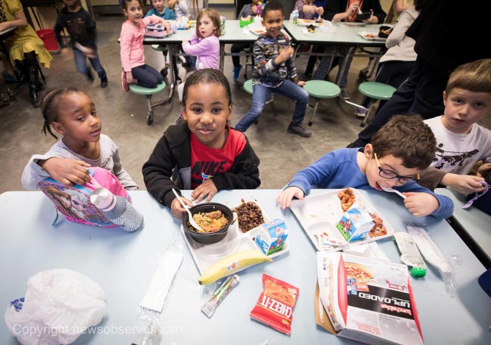 Demani Dargan-Juarez, 5, center, looks up in between bites of school lunch at George Watts Elementary School on Thursday, Jan. 24, 2019.