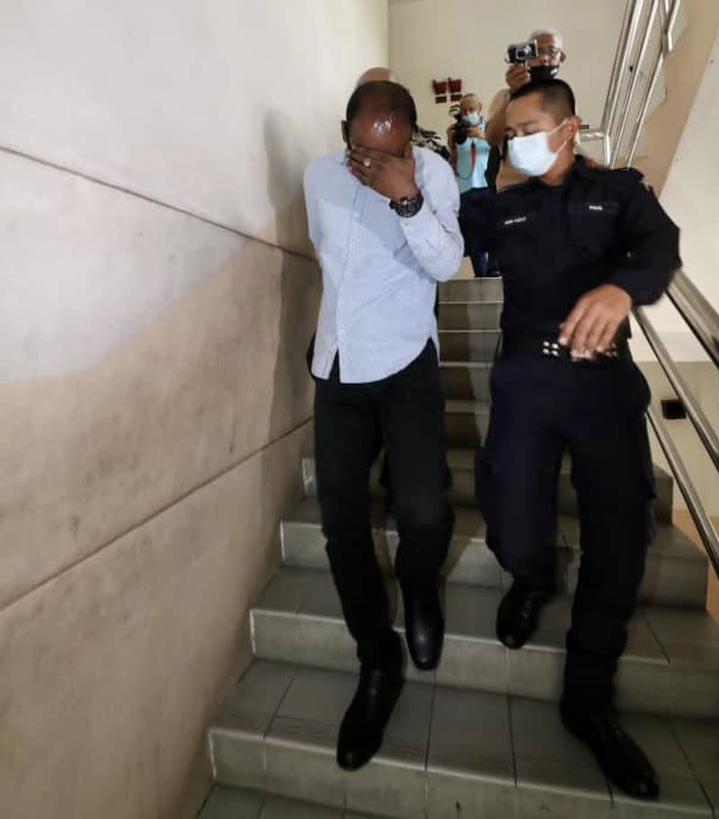 The accused G. Viswanathan (left) being escorted by a policeman to the Johor Baru Sessions Court in Johor Baru today on charges of abusing his son about three years ago. — Picture by Ben Tan