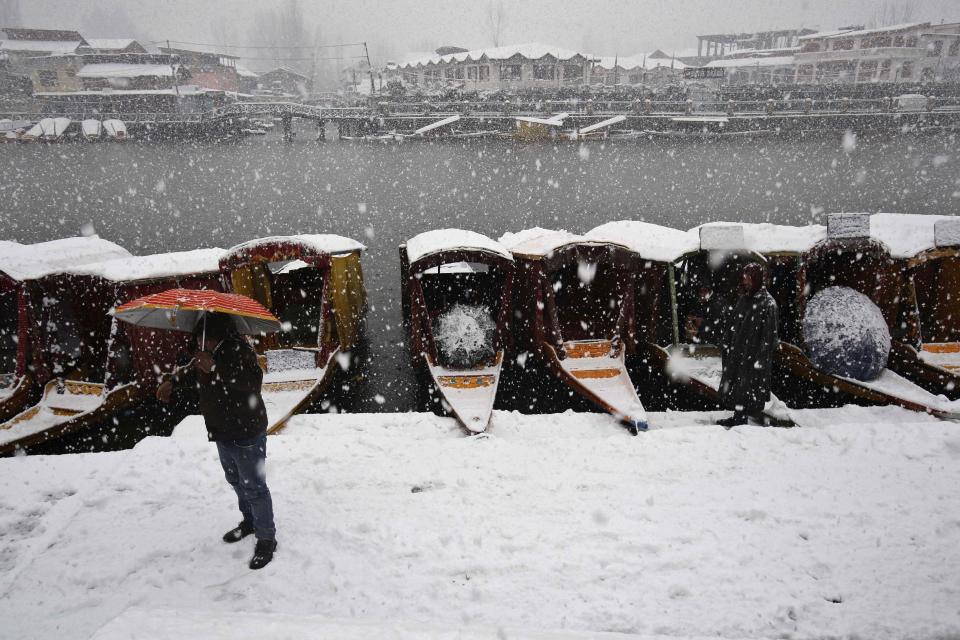 An Indian tourist talks on his cellphone on the banks of the Dal Lake as it snows in Srinagar, India, Tuesday, March 11, 2014. The Kashmir valley was Tuesday cut off from rest of India due to heavy snowfall. (AP Photo/Mukhtar Khan)