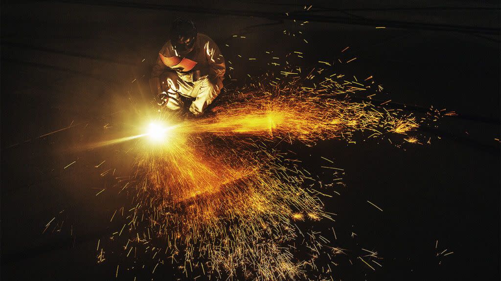 Welders working on cutting metal as sparks fly