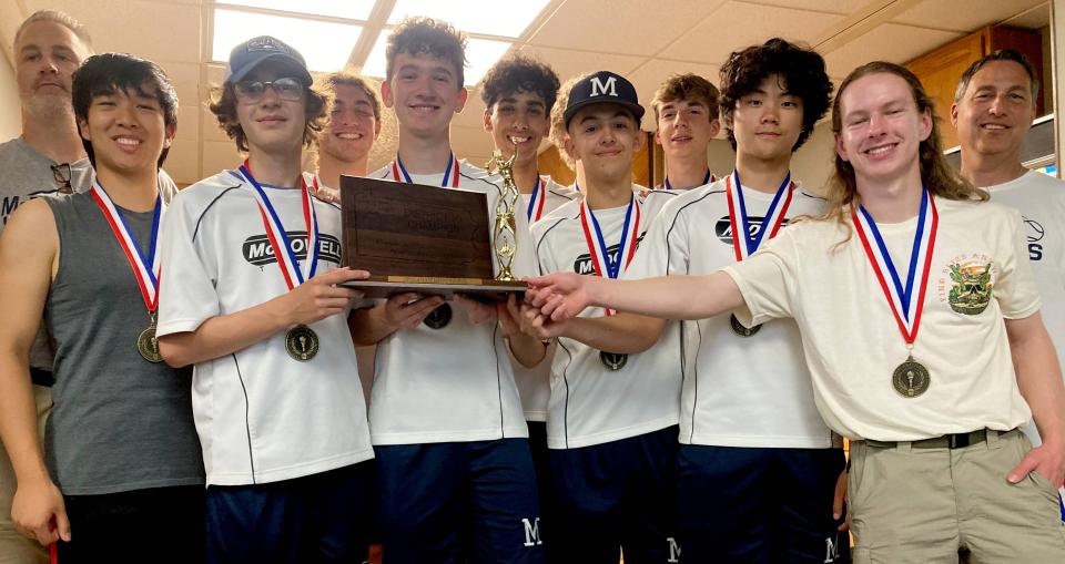 Members of the McDowell boys tennis team, led by coach Andy Heinlein (far right), pose with the District 10 trophy they received for winning Friday's Class 3A tournament final at Westwood Racquet Club. The Trojans defeated Erie High 4-1.