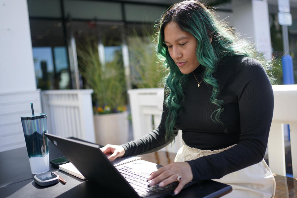 Daniella Malave works on her laptop at a coffee shop in Sea Girt, N.J., Thursday, Sept. 29, 2022. While working full time for Chipotle, Malave completed two years of community college with annual stipends of $5,250 from the restaurant chain. After that, she enrolled in the company’s free online college program, through which she earned a bachelor’s degree in business management from Wilmington University in 2020. (AP Photo/Seth Wenig)