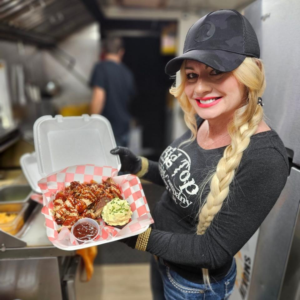 Pitmaster Lora M. Rust poses with an order of freshly prepared barbecue while inside her food truck Smokin Momma Lora's BBQ Mobile on Dec. 31, 2023 in downtown Bradenton.