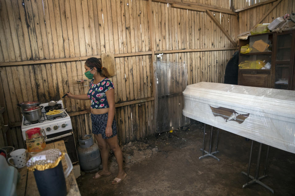 Liliana Blas fries a batch of potatoes for lunch next to the coffin that contains the remains of her grandmother Susana Cifuentes, who died at the age of 71 from symptoms related to COVID-19, inside her house in the Shipibo Indigenous community of Pucallpa, in Peru’s Ucayali region, Tuesday, Sept. 1, 2020. Decades of underinvestment in public health care, combined with skepticism of modern medicine, mean many are not getting standard treatments like oxygen therapy to treat severe virus cases. (AP Photo/Rodrigo Abd)