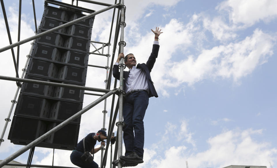 FILE - In this March 4, 2019 file photo, National Assembly President Juan Guaidó, an opposition leader who declared himself interim president, waves to supporters from the scaffolding after speaking at a rally demanding the resignation of Venezuelan President Nicolas Maduro in Caracas, Venezuela. A defiant Guaidó returns home to Venezuela and urges supporters at a rally to intensify their campaign to topple the government. AP Photo/Fernando Llano, File)