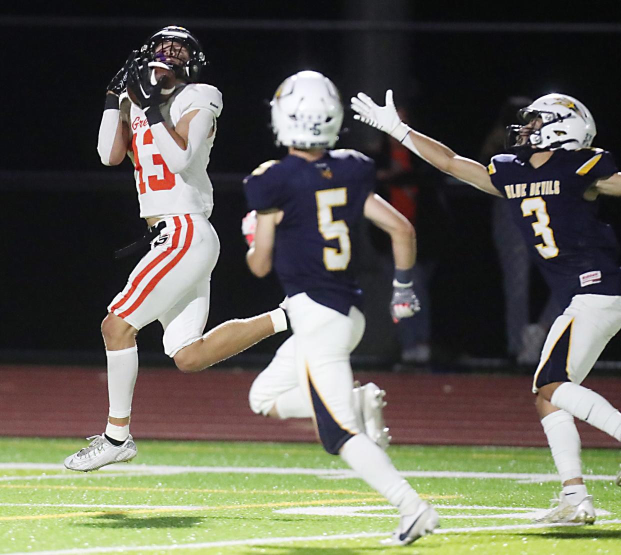 Green's Zachary Baglia catches a second-half touchdown pass as Tallmadge's Caleb Reifsnyder and Constantine Detorakis defend in a 2023 game.