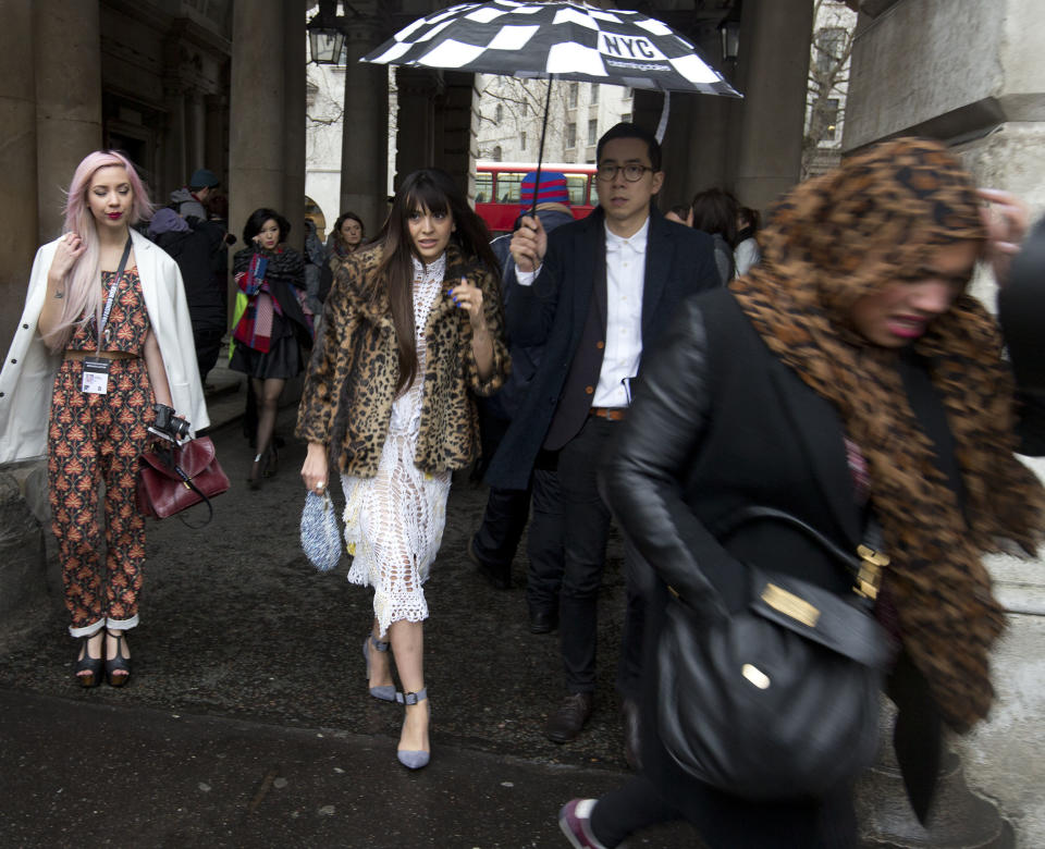 People arrive carrying umbrellas for the first day of London Fashion Week, in London, Friday, Feb. 14, 2014. (AP Photo/Alastair Grant)