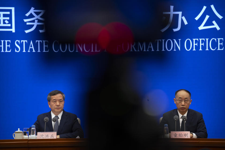 Shen Hongbing, the director of the Chinese Center for Disease Control and Prevention, left, listens as Tong Yigang, dean of the College of Life Science and Technology at Beijing University of Chemical Technology, speaks at a press conference on the origins of COVID-19 at the State Council Information Office in Beijing, Saturday, April 8, 2023. (AP Photo/Mark Schiefelbein)