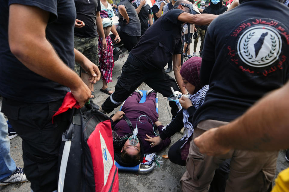 Civil defense workers give oxygen to a woman who fainted from the tear gas during a demonstration in solidarity with the Palestinian people in Gaza, near the U.S. embassy in Aukar, a northern suburb of Beirut, Lebanon, Wednesday, Oct. 18, 2023. (AP Photo/Hassan Ammar)