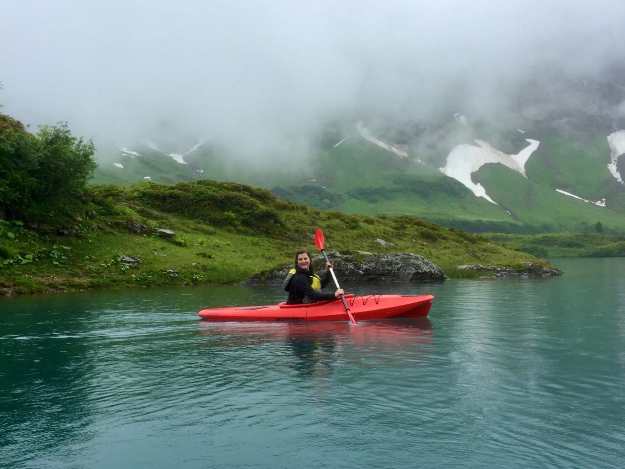 Woman kayaking on red kayak in Switzerland.