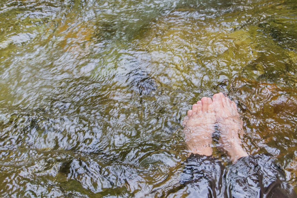 Two bare feet Soaking in a stream of pure water that occurs in nature.