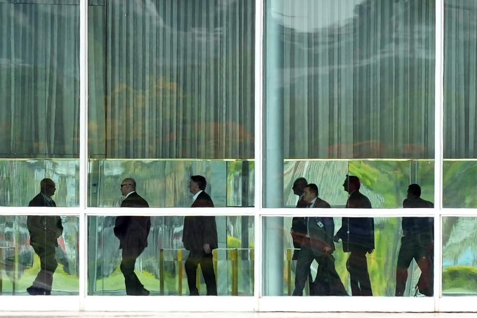 Brazilian President Jair Bolsonaro, third from left, leaves his official residence of Alvorada Palace to go to his office at Planalto palace in Brasilia, Brazil, Monday, Oct. 31, 2022, the morning after losing reelection to former Brazilian President Luiz Inacio Lula da Silva. (AP Photo/Eraldo Peres)