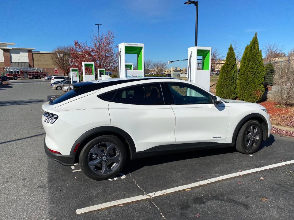 A white Ford Mustang Mach-E at a charger in a parking lot.