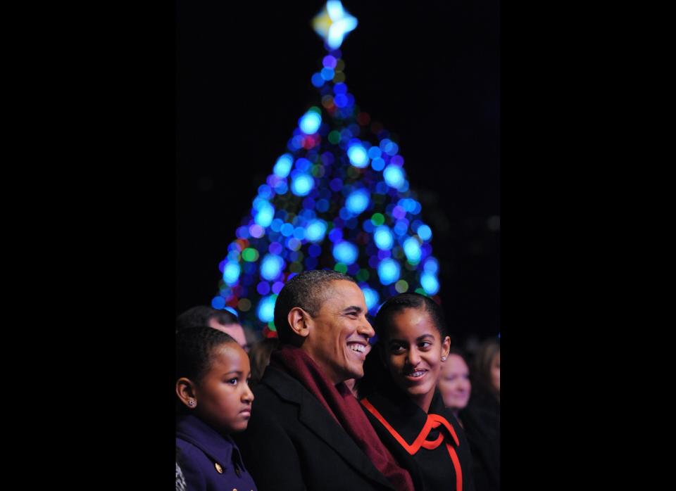 U.S. President Barack Obama smiles with daughters Sasha (L) and Malia (R) while watching First Lady Michelle Obama read to children during the annual lighting of the National Christmas tree on December 1, 2011 at The Ellipse in Washington, D.C. (MANDEL NGAN/AFP/Getty Images)  