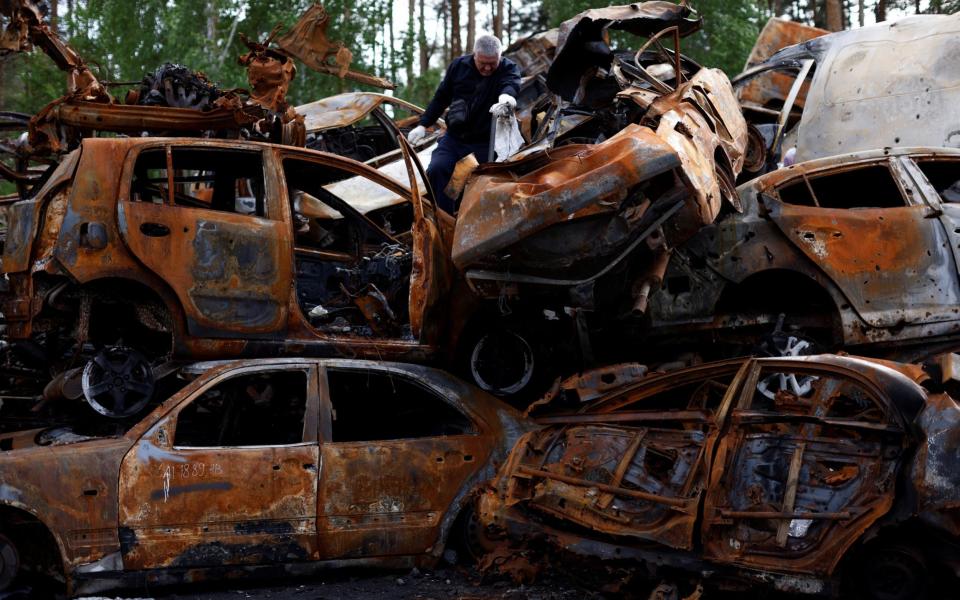 A man looks through cars that were destroyed during the war in Irpin - EDGAR SU /REUTERS