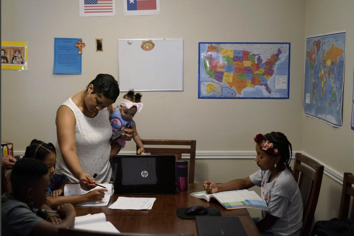 Arlena Brown, center, holds her youngest child, Lucy, 9 months, as she leads their other children, from left, Jacoby, 11; Felicity, 9, and Riley, 10, through math practice at their home in Austin, Texas, Tuesday, July 13, 2021. Arlena worked as a preschool teacher before the pandemic. “In the beginning, the biggest challenge was to unschool ourselves and understand that homeschooling has so much freedom,” she said. “We can go as quickly or slowly as we need to.” (AP Photo/Eric Gay)