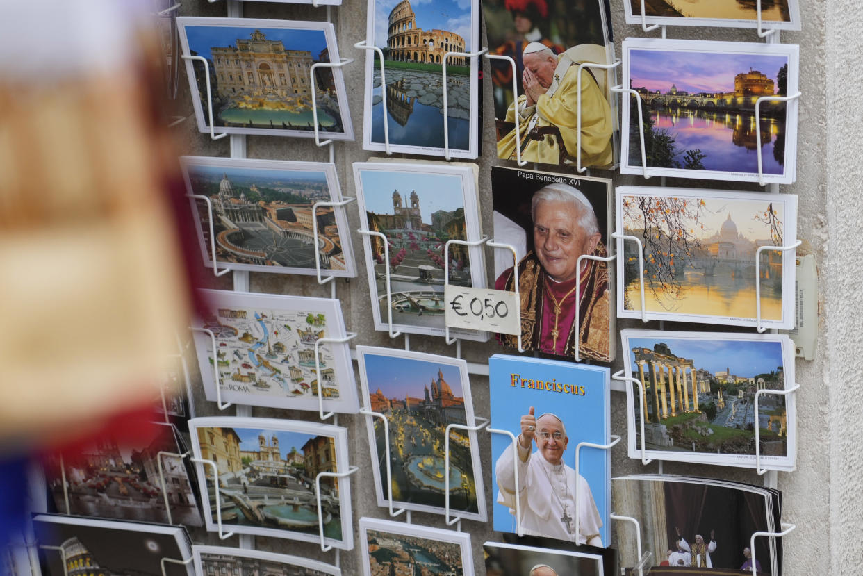 Postcards of Pope Benedict XVI, Pope Francis and Pope John Paul II are sold at a kiosk while the body of late Pope Emeritus Benedict XVI laid out in state inside St. Peter's Basilica at The Vatican, Monday, Jan. 2, 2023. Benedict XVI, the German theologian who will be remembered as the first pope in 600 years to resign, has died, the Vatican announced Saturday. He was 95(AP Photo/Gregorio Borgia)