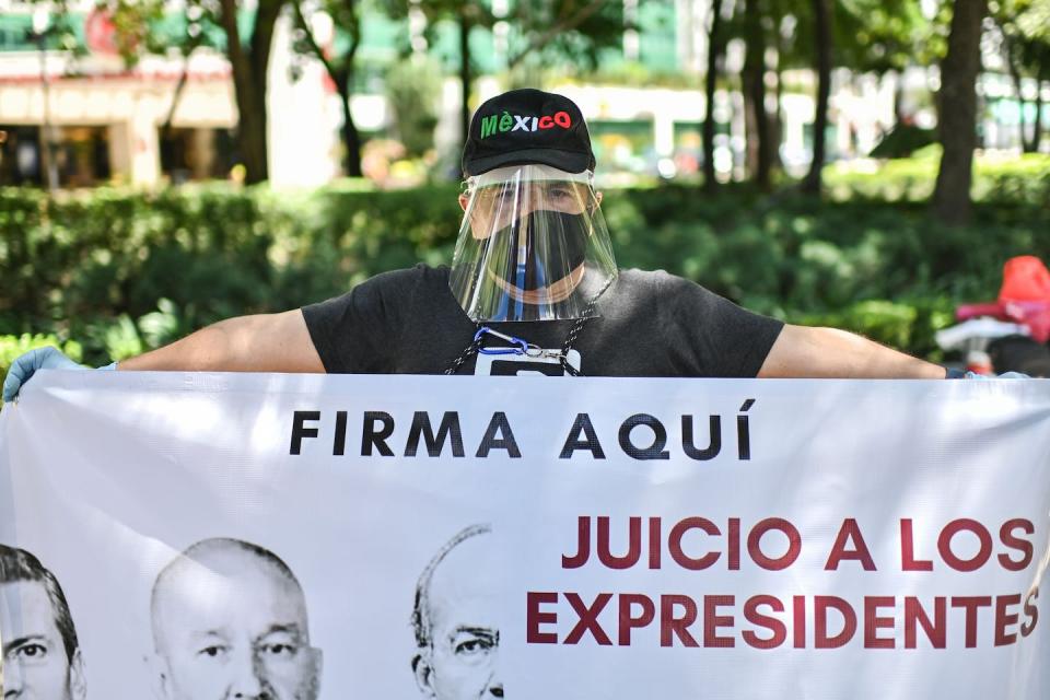 A protester in Mexico City calls for the prosecution of several former presidents implicated in a corruption scandal. <a href="https://www.gettyimages.com/detail/news-photo/an-activist-displays-a-banner-during-the-collection-of-news-photo/1228287609?adppopup=true" rel="nofollow noopener" target="_blank" data-ylk="slk:Pedro Pardo/AFP via Getty Images;elm:context_link;itc:0;sec:content-canvas" class="link ">Pedro Pardo/AFP via Getty Images</a>