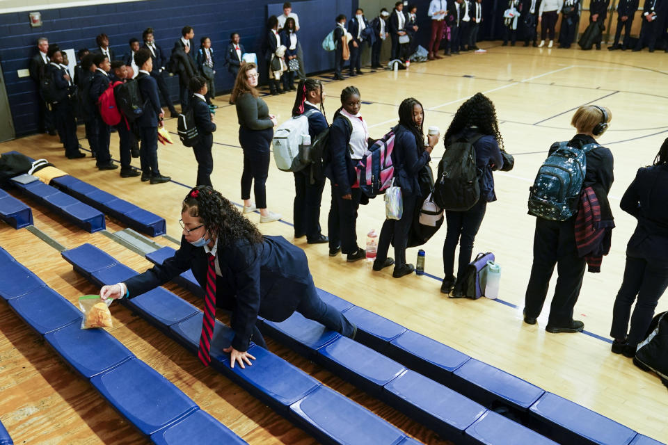 Annii Kinepoway cleans the bleachers at St. Marcus Lutheran School during the school's morning prayer as part of her leadership task Wednesday, Oct. 19, 2022, in Milwaukee. Annii’s mother could only afford this educational opportunity because of school choice programs. (AP Photo/Morry Gash)