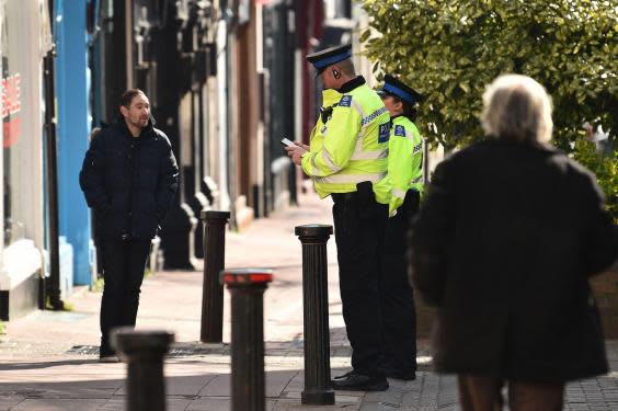 Police community support officers talk to a man on a street in Brighton, southern England on March 24, 2020 after the British government ordered a lockdown to help stop the spread of coronavirus (GLYN KIRK/AFP via Getty Images)