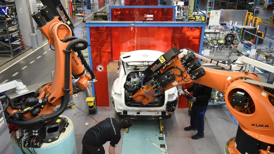 Mitarbeiter von Mercedes-Benz überwachen im Werk in Bremen, wie ein Roboter in das C-Klasse Hybrid Modell eine Batterie einsetzt. Foto: Carmen Jaspersen