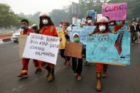 Youths walk with placards through the main road during a Global Climate Strike rally as smog covers the city due to the forest fires in Palangka Raya