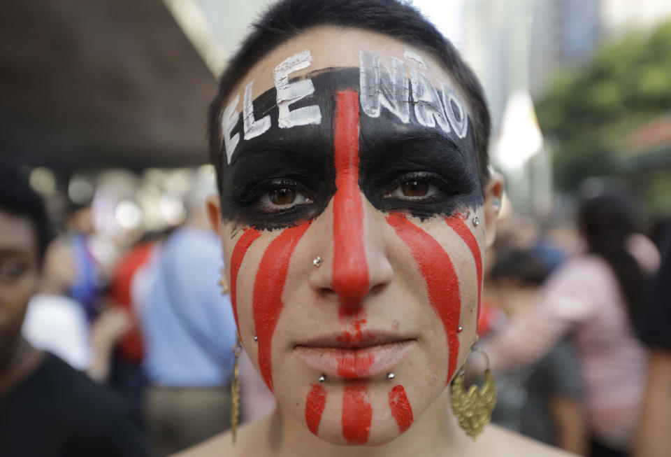 FILE - In this Oct. 20, 2018 photo, a woman poses for a photo with the words "Not him" written in Portuguese on her forehead, during one of many protests against the presidential frontrunner Jair Bolsonaro, in Sao Paulo, Brazil. Bolsonaro will face off with Workers' Party candidate Fernando Haddad who has promised to put social and economic inclusion at the heart of his agenda. (AP Photo/Andre Penner, File)