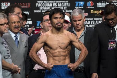 Manny Pacquiao (C) of the Philippines poses on the scales during an official weigh-in for his World Boxing Organisation (WBO) 12-round welterweight title fight against Chris Algieri of the U.S. at the Venetian Macao hotel in Macau November 22, 2014. REUTERS/Tyrone Siu/Files