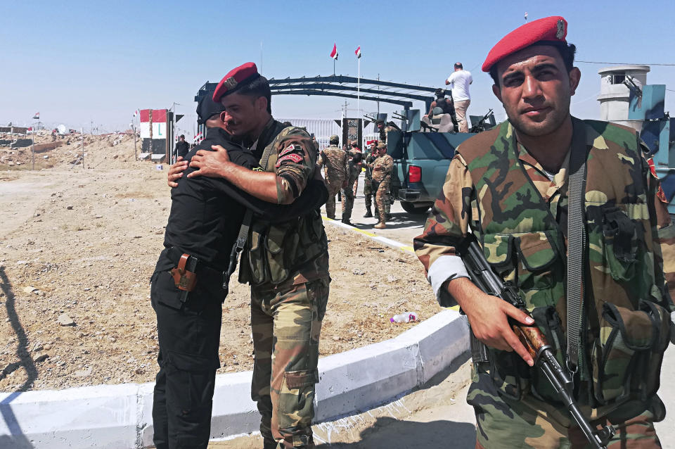 Iraq and Syria border guards soldiers congratulate each other during the opening ceremony of the crossing between the Iraqi town of Qaim and Syria's Boukamal in Anbar province, Iraq, Monday, Sept. 30, 2019. Iraq and Syria have opened a key border crossing between the two neighboring countries seven years after it was closed during Syria's civil war. (AP Photo/Hadi Mizban)
