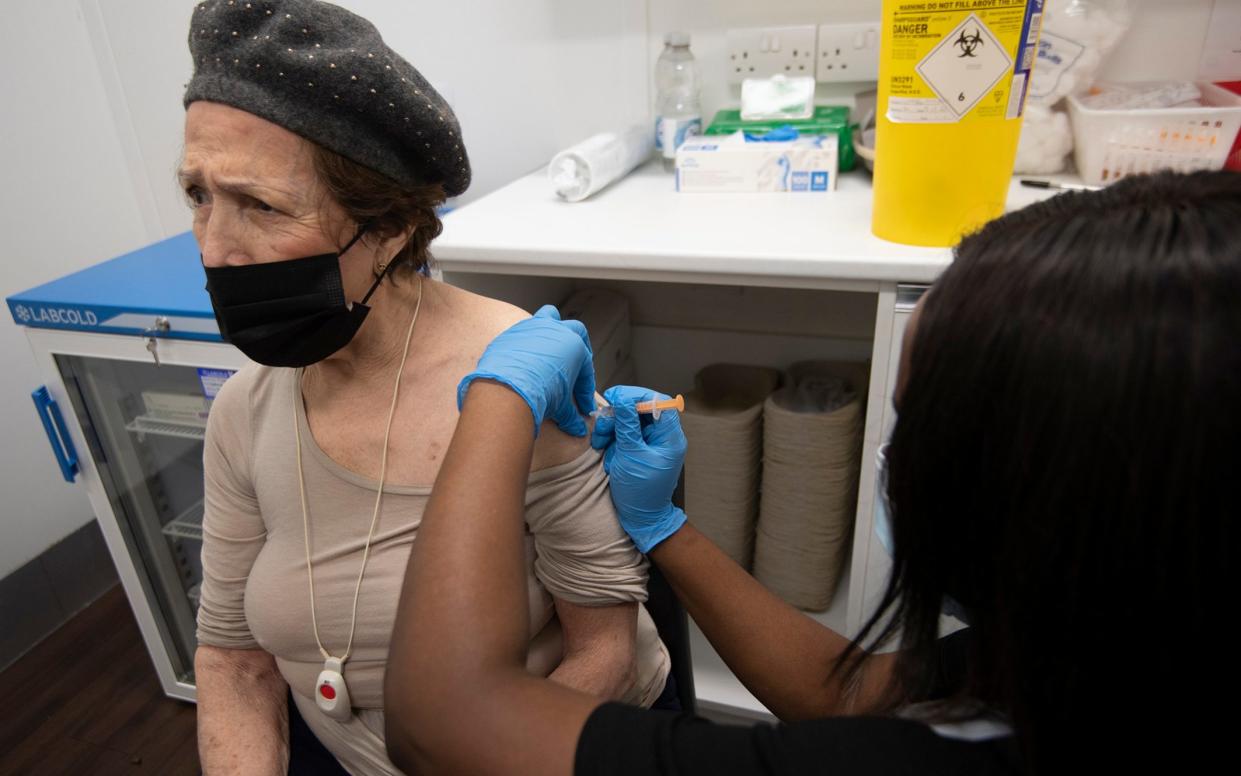 Guildford resident Meris Cox, 80, is vaccinated by Superdrug branch manager Christine Zemba -  Eddie Mulholland for The Telegraph