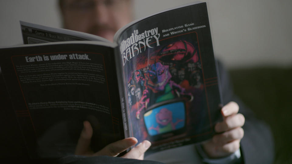 A person reading a copy of the role-playing guidebook 'The Jihad to Destroy Barney'