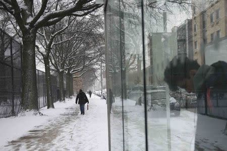 A woman walks down a sidewalk outside the Marcy Houses public housing development in the Brooklyn borough of New York January 9, 2015. REUTERS/Stephanie Keith