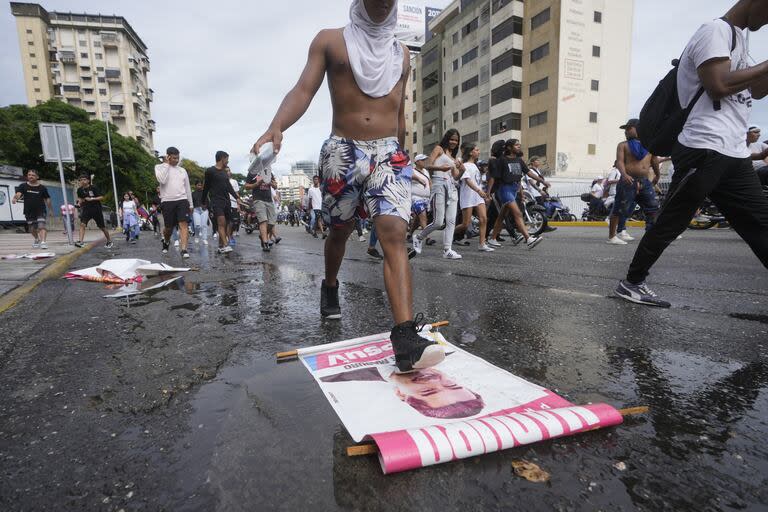 Un manifestante pisa un cartel de campaña del presidente Nicolás Maduro durante una marcha contra su declaración ganadora de las elecciones presidenciales, el día después de la votación en Caracas.