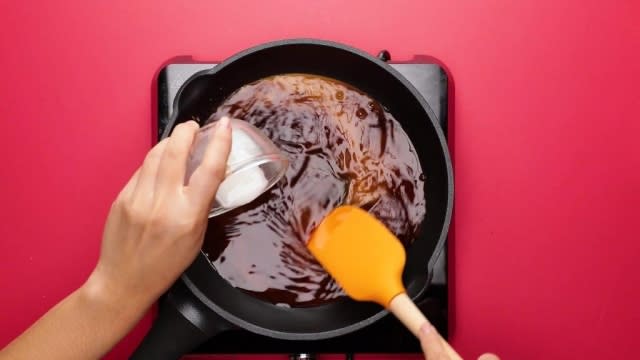 Pouring and stirring cornflour water into sauce with spatula