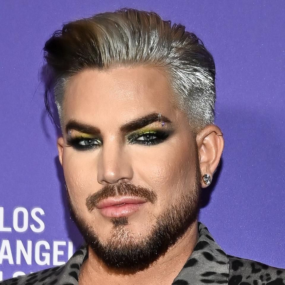 Adam Lambert wearing a leopard print jacket and bold eye makeup at an event