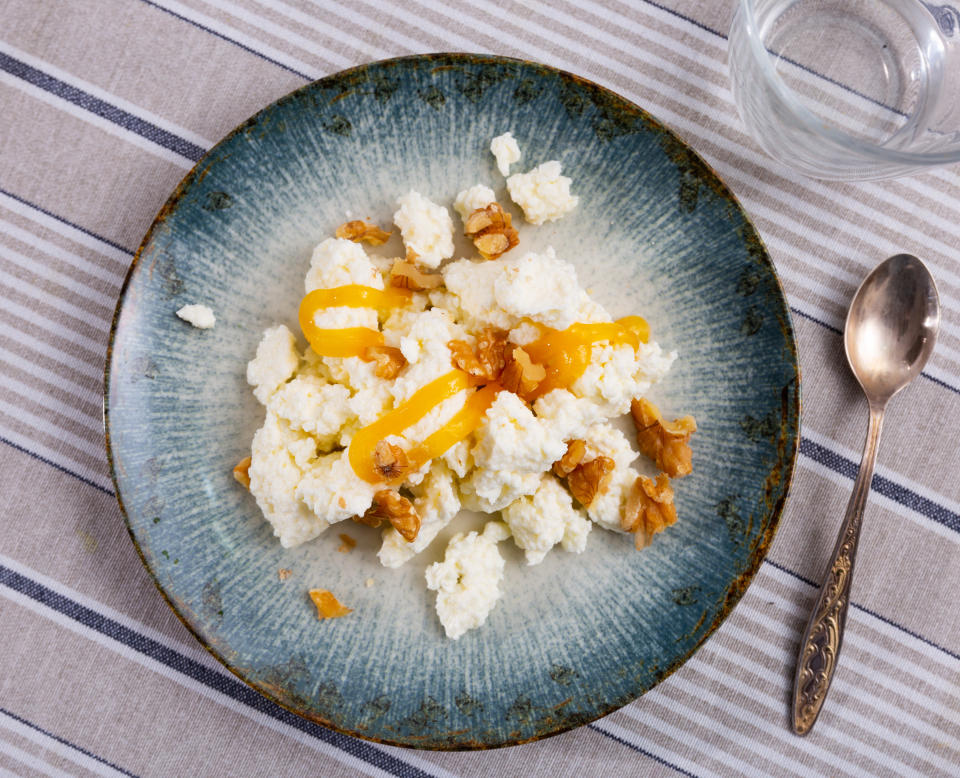 An image of some cottage cheese with honey drizzle and pecans on a blue plate