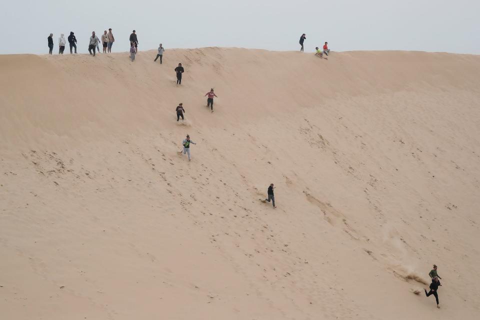 Tourists run downhill at Silver Lake State Park in Mears on Sept. 26, 2020.