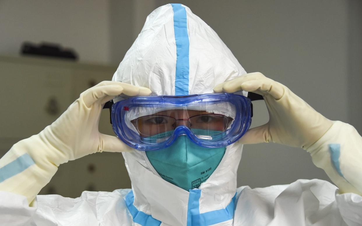 A laboratory worker checks her goggles before testing coronavirus samples - Rex/Xinhua